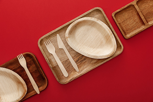 top view of rectangular wooden dishes with plates and cutlery on red background