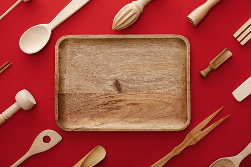 top view of natural rectangular  wooden dish on red background with kitchenware
