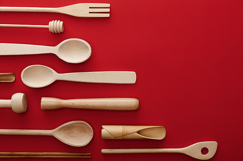 top view of natural wooden spoons and kitchenware on red background with copy space