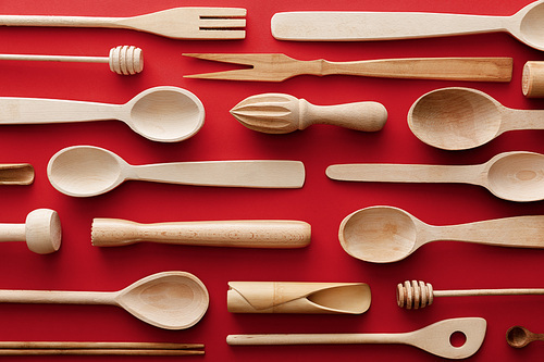 top view of natural wooden spoons and kitchenware on red background