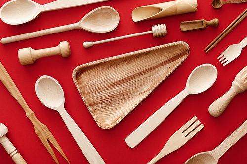 top view of empty triangle wooden dish on red background with kitchenware
