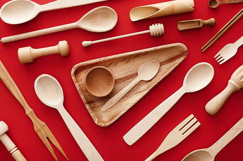 top view of  triangle wooden dish with cup and spoon on red background with kitchenware