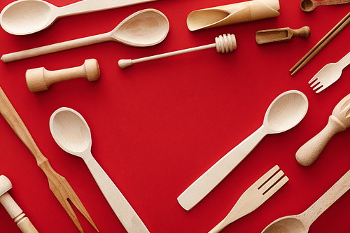 top view of spoons, forks, chopsticks and kitchenware on red background with copy space