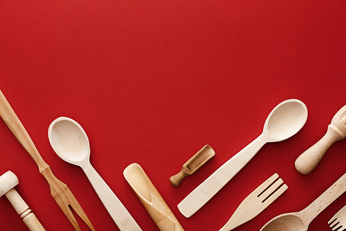 top view of woden spoons, forks, chopsticks and kitchenware on red background with copy space