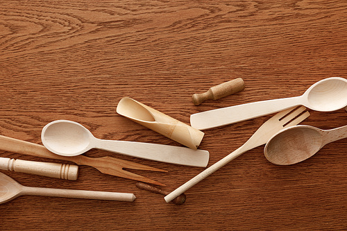 top view of wooden cutlery and kitchenware on brown background