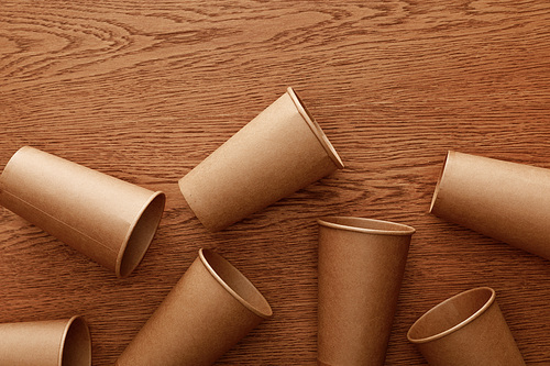 top view of empty paper cups on brown wooden background
