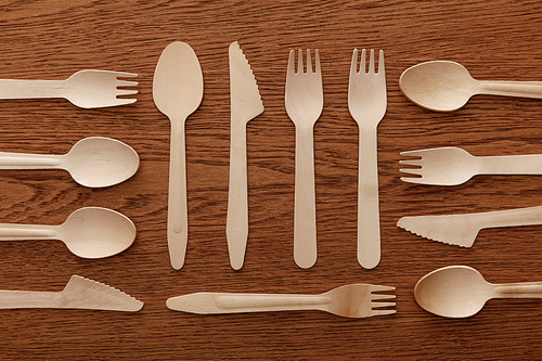 top view of wooden spoons forks and knifes on brown background