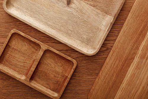 top view of wooden dishes and cutting board on brown background