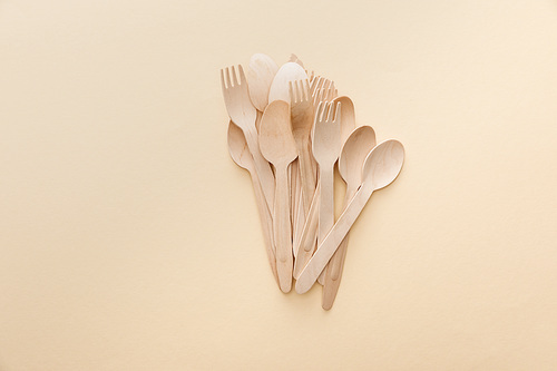 top view of natural wooden spoons and forks on beige background