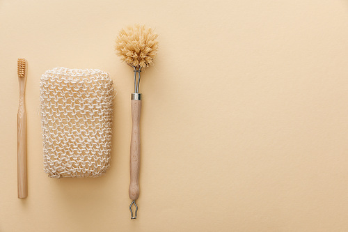 top view of natural bath sponge near toothbrush and body brush on beige background