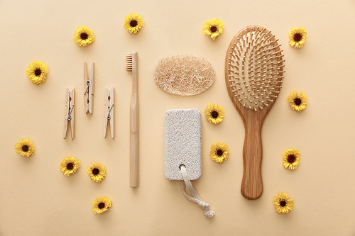 top view of wooden clothespins, toothbrush, hairbrush, pumice stone and loofah on beige background with flowers