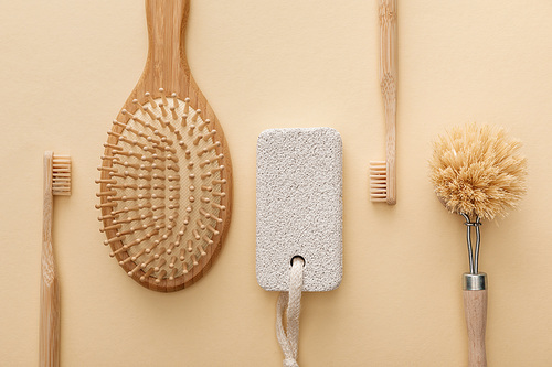 top view of toothbrushes, hairbrush, body brush and pumice stone on beige background