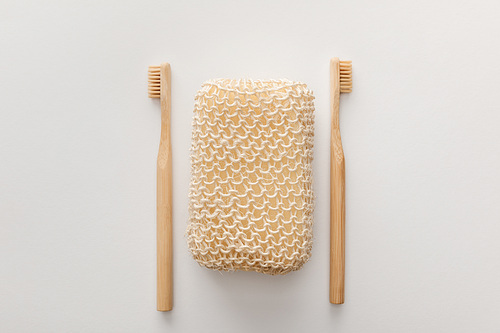 top view of wooden toothbrushes and bath sponge on white background