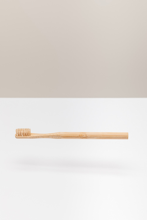 natural wooden toothbrush above white surface isolated on gray