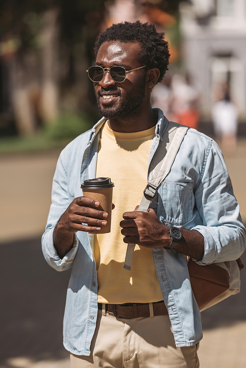 stylish, cheerful african american man looking away while holding disposable cup