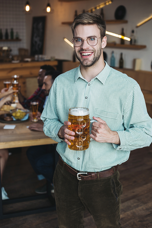 handsome young man holding mug of light beer and smiling at camera