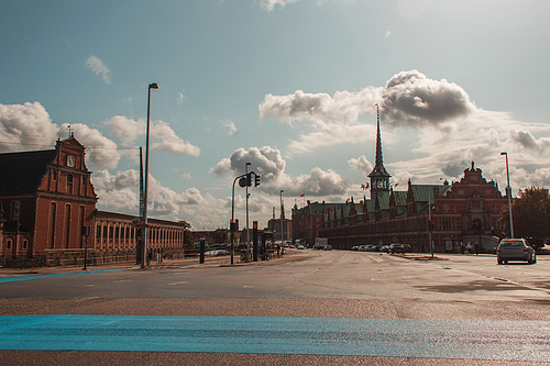 Urban street with facade of Borsen building and cloudy sky at background in Copenhagen, Denmark
