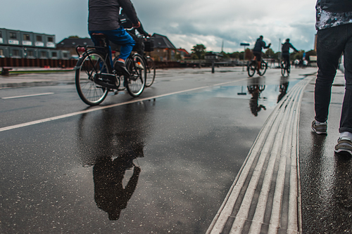 Selective focus of people walking and riding bicycles on urban street during rain in Copenhagen, Denmark