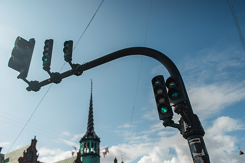 Low angle view of traffic lights with cloudy sky at background on urban street in  Copenhagen, Denmark