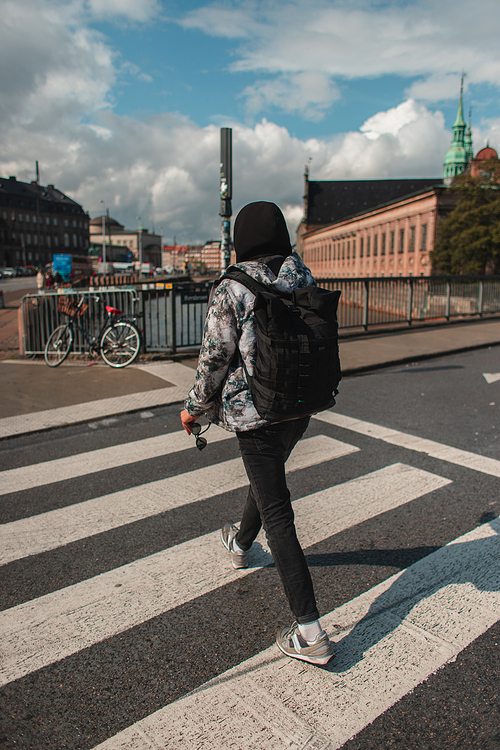 Back view of man walking on crossroad on sunlit street in Copenhagen, Denmark