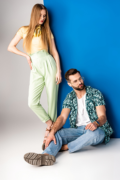 beautiful stylish couple posing in summer clothes on grey and blue