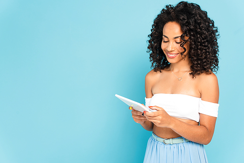 happy african american woman using digital tablet on blue