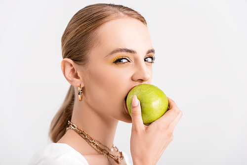 blonde woman biting green apple and  isolated on white