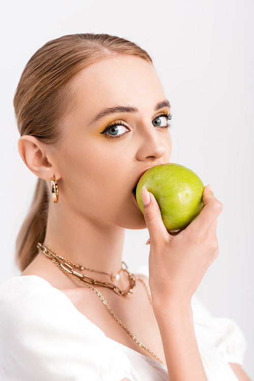 blonde woman biting green apple isolated on white