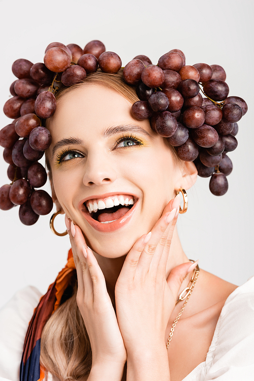 rustic blonde woman with grapes on head laughing isolated on white