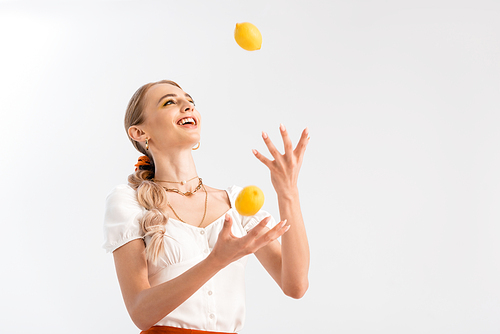 blonde woman juggling with yellow lemons isolated on white