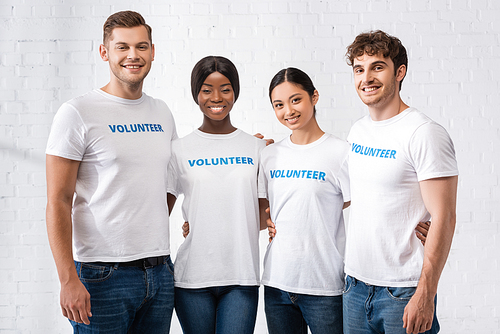 Young multicultural volunteers embracing in charity center
