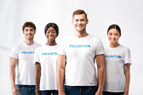 Young multiethnic volunteers in t-shirts with lettering  in charity center