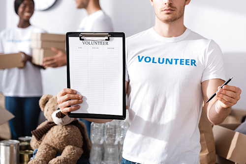 Selective focus of volunteer holding clipboard and pen in charity center