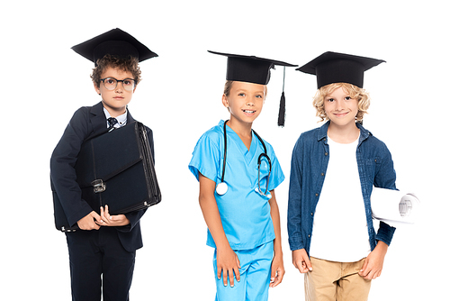 kids in graduation caps dressed in costumes of different professions holding blueprint and briefcase isolated on white