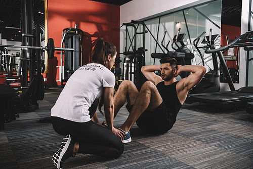 young trainer instructing handsome sportsman doing push ups