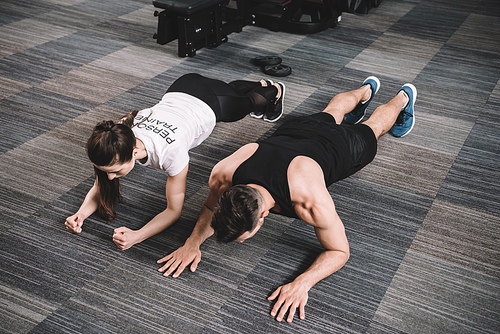 young trainer doing plank exercise together with sportsman