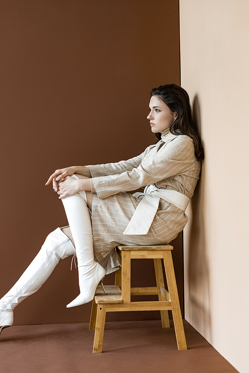 side view of beautiful and trendy woman sitting on stairs, looking away
