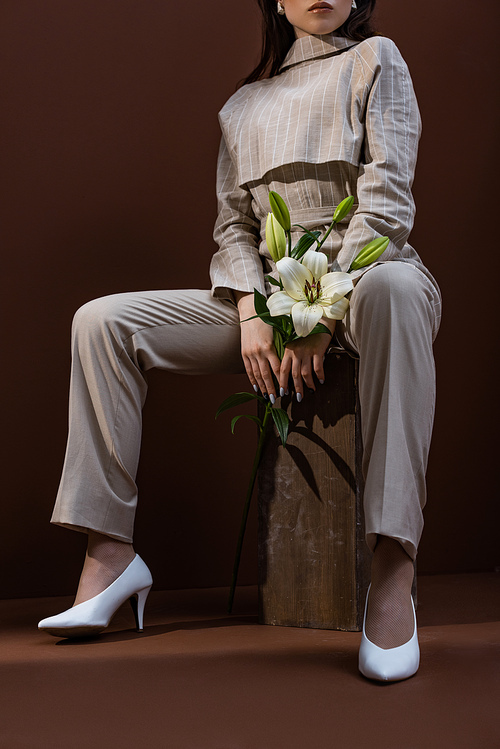 low angle view of fashionable woman with flower in hands sitting on box