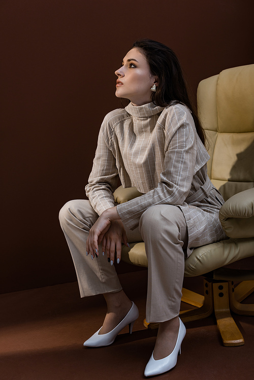 fashionable woman sitting on armchair ,looking away