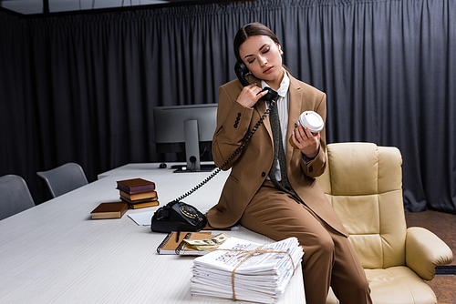 adult businesswoman with paper cup in hand closing eyes, talking on phone