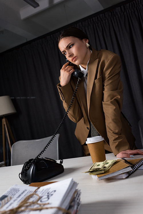 low angle view of sad businesswoman with handset in hand talking on telephone, looking away