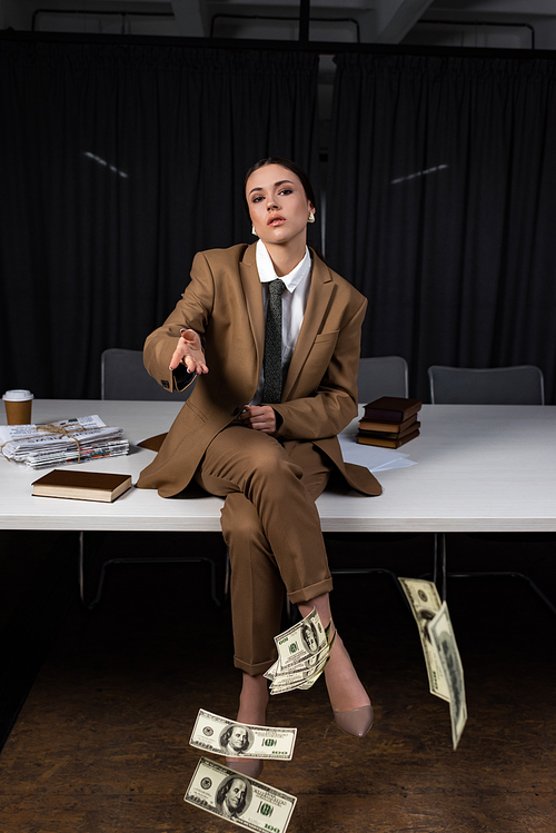 adult businesswoman sitting on table, crossing legs,  and throwing money