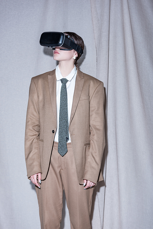 successful woman in vr headset standing on light grey curtain background