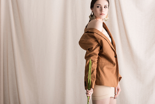 fashionable woman standing on curtain background, looking away