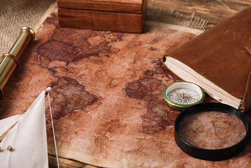 old world map near telescope, leather notebook and compass on hessian
