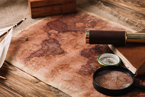 world map near telescope and magnifying glass on wooden surface