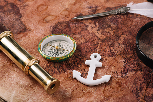 compass, white anchor, nib and telescope on world map