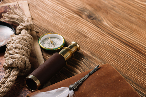 rope cable, nib, compass and telescope on wooden surface