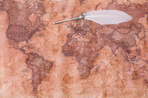 top view of nib with white feather on ancient world map