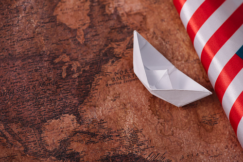 white paper boat near American national flag on ancient world map